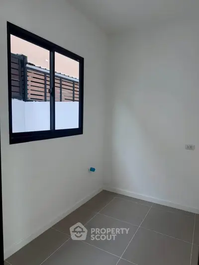 Minimalist small room with window and tiled floor, perfect for storage or utility use.