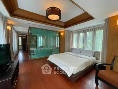 Luxurious bedroom with wooden flooring and large windows, featuring a glass-enclosed bathtub area for a unique design.