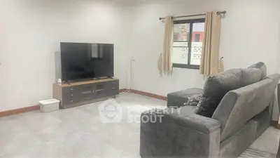 Spacious living room with modern TV setup and cozy gray sofa, perfect for relaxation.