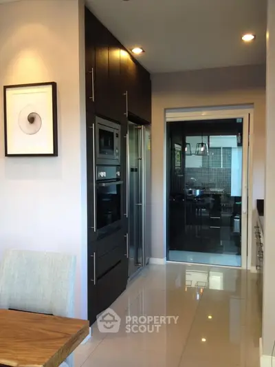 Modern kitchen with sleek appliances and glossy floor tiles, featuring a stylish open layout design.