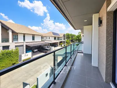 Spacious balcony with glass railing offering a stunning view of modern residential neighborhood.