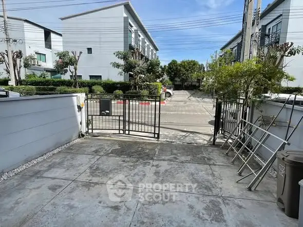 Modern townhouse entrance with gated driveway and clear blue sky.