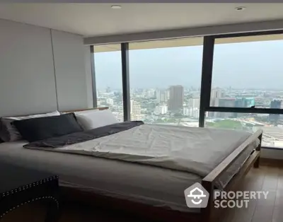 Luxurious high-rise bedroom with panoramic city views through floor-to-ceiling windows, offering a serene urban retreat.