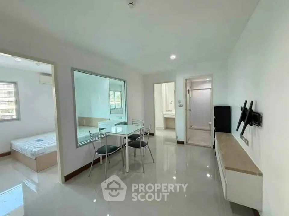 Modern apartment interior with dining area and bedroom view, sleek design and bright lighting.