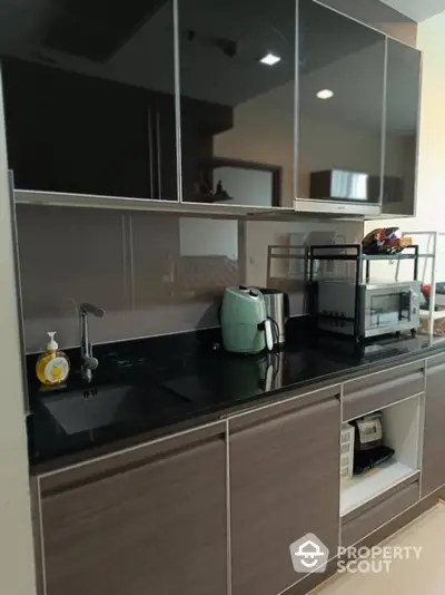 Modern kitchen with sleek cabinetry and appliances, featuring a stylish black countertop and ample storage space.