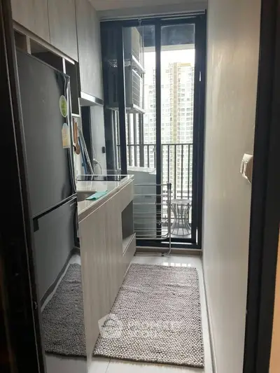 Compact kitchen with modern appliances and balcony view in urban apartment.