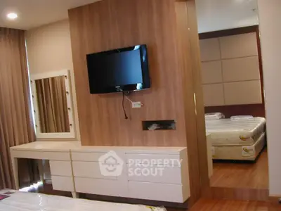 Modern bedroom with wall-mounted TV and stylish vanity in a cozy apartment.