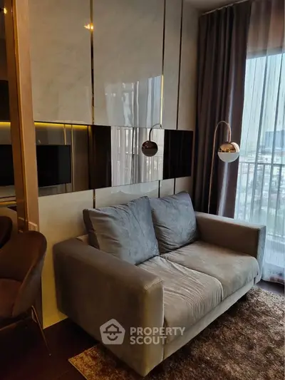 Modern living room with cozy gray sofa and elegant lighting, featuring floor-to-ceiling windows with city view.