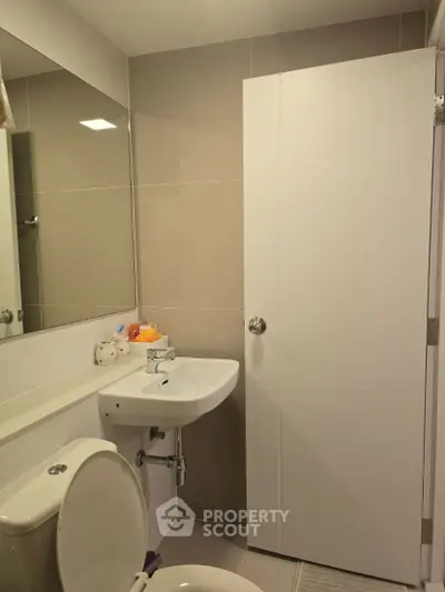 Modern bathroom with sleek design, featuring a compact sink and toilet.