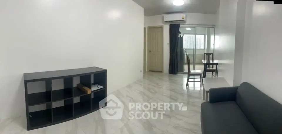 Modern minimalist living room with sleek furniture and marble flooring in a bright apartment.