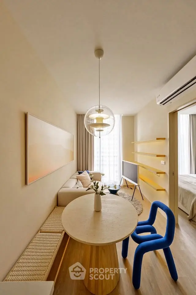 Modern living room with stylish furniture and natural light, featuring a unique blue chair and elegant decor.