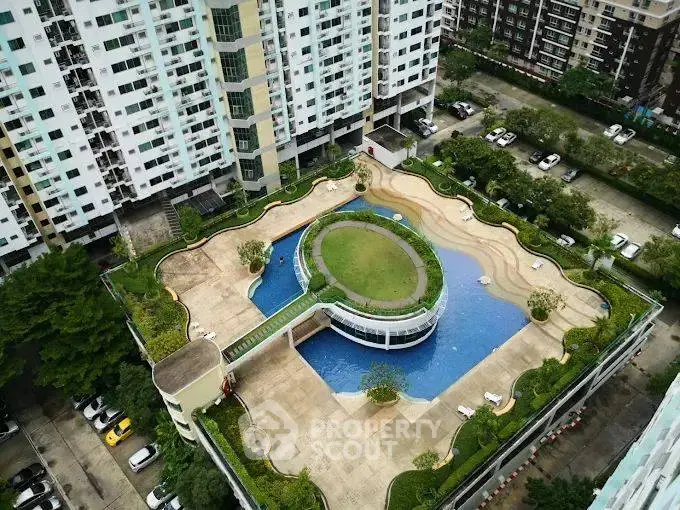 Stunning aerial view of modern apartment complex with unique rooftop pool and lush greenery.