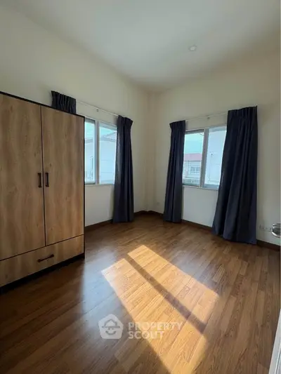 Spacious bedroom with wooden flooring and ample natural light