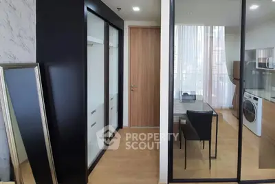 Modern apartment interior with glass partitions and washing machine in sleek kitchen area.