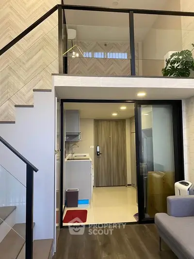 Modern duplex apartment with stylish staircase and open living area, featuring sleek design and ample natural light.