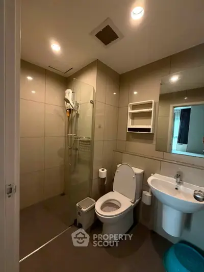 Modern bathroom with sleek fixtures and glass shower in contemporary apartment.