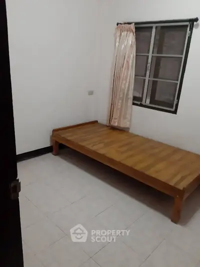 Minimalist bedroom with wooden bed frame and tiled floor, perfect for cozy living.