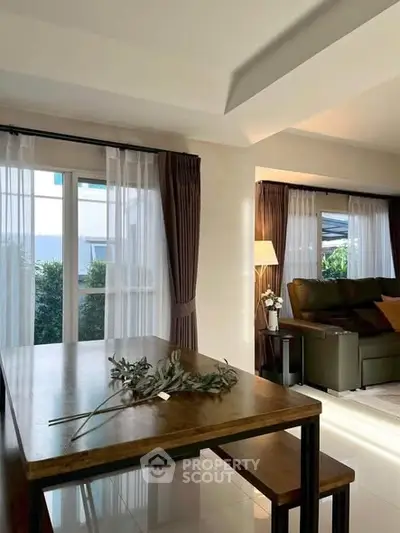 Spacious living room with natural light and elegant dining area, perfect for modern living.