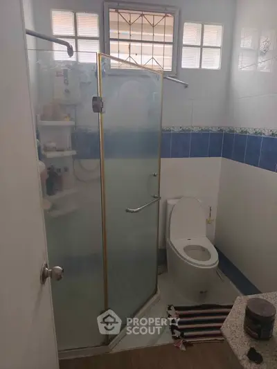 Compact bathroom with glass shower enclosure and modern toilet in cozy home.