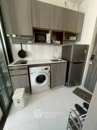 Modern compact kitchen with washing machine and fridge in stylish apartment
