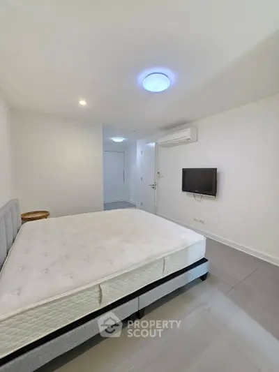 Spacious modern bedroom with minimalist design and wall-mounted TV
