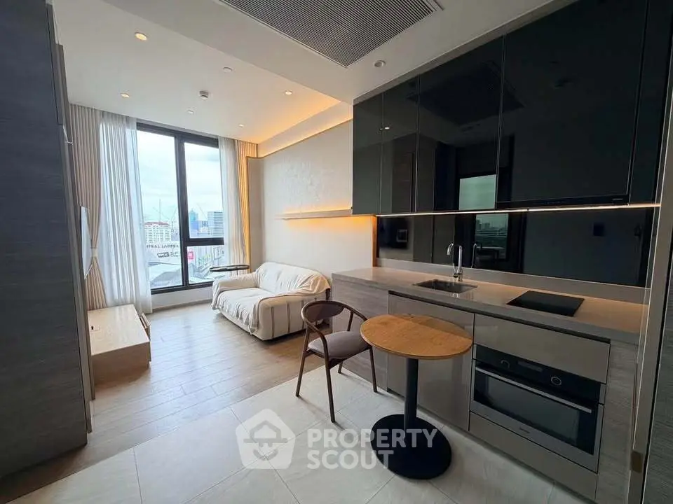 Modern open-layout studio with sleek kitchen and cozy living area, featuring large windows and stylish furnishings.