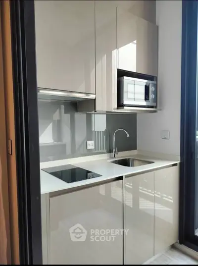 Modern compact kitchen with sleek cabinetry and built-in appliances in a stylish apartment.