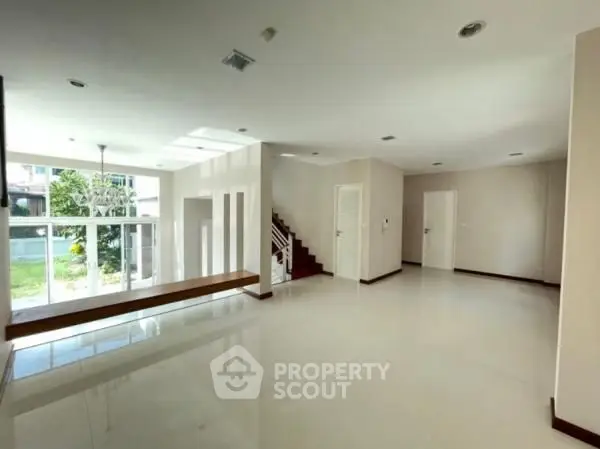 Spacious modern living room with large windows and staircase