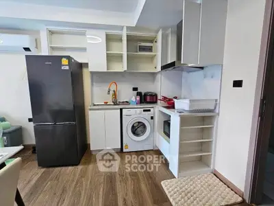 Modern kitchen with appliances including fridge, washing machine, and microwave in a compact layout.