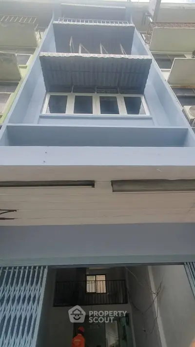 Modern blue building exterior with balconies and awnings, showcasing urban architectural design.