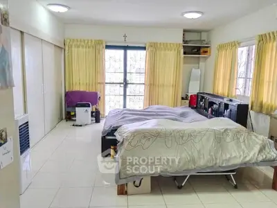 Spacious bedroom with large windows and ample natural light, featuring cozy bedding and modern decor.