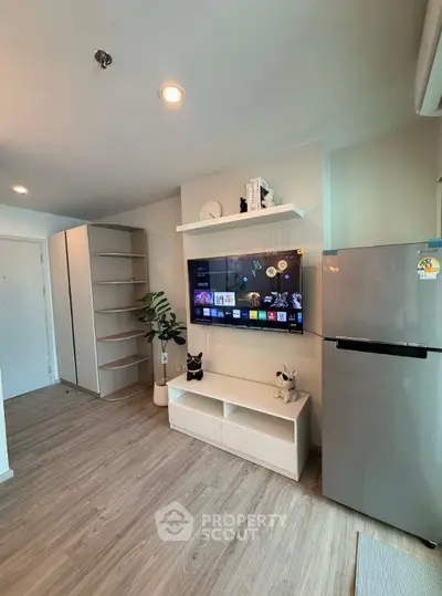 Modern living room with sleek TV setup and stainless steel fridge, perfect for urban living.