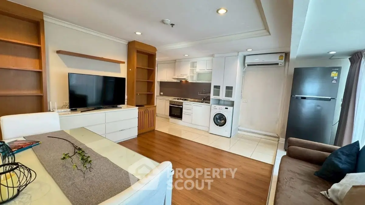 Modern open-plan living room with kitchen, featuring sleek appliances and stylish decor.