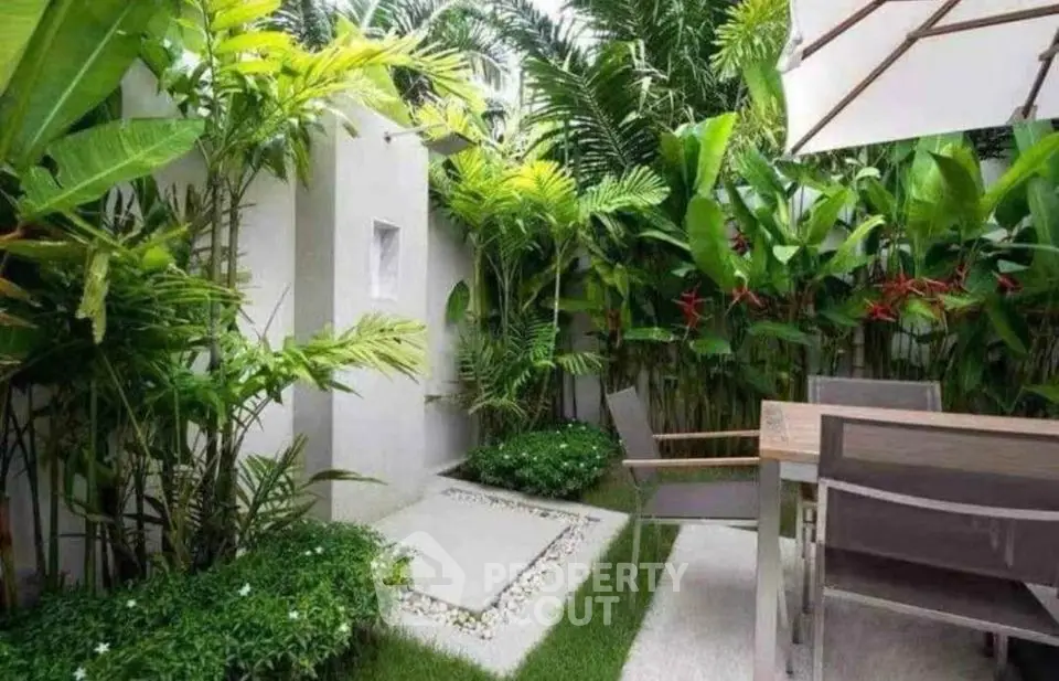 Lush garden patio with tropical plants and outdoor dining set
