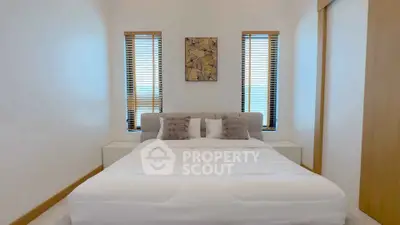 Cozy bedroom with modern decor and natural light from two windows.