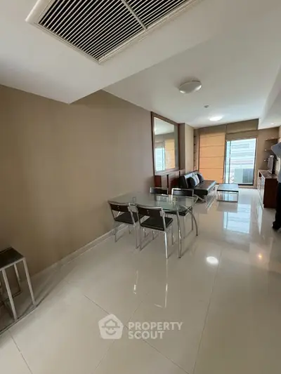 Modern living room with glass dining table and sleek furniture in a bright apartment.