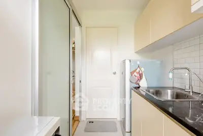 Modern kitchen with sleek cabinetry and stainless steel sink in compact layout.