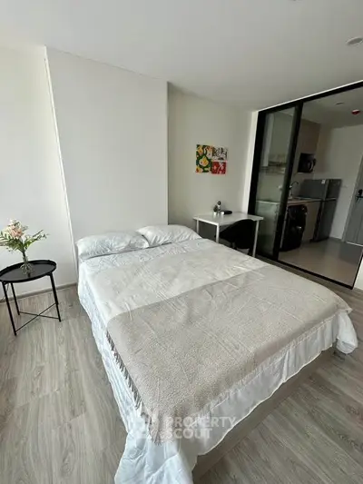 Modern bedroom with cozy bed and open kitchen view, perfect for urban living.