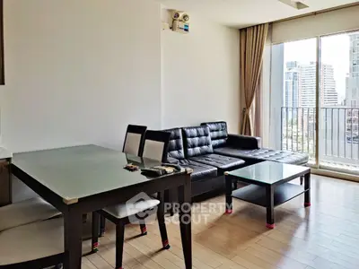 Modern living room with sleek black leather sofa and city view from balcony.