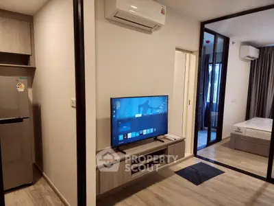 Modern apartment interior with sleek design, featuring a living area with TV and air conditioning, leading to a cozy bedroom.