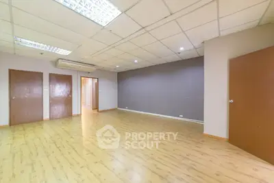 Spacious empty room with wooden flooring and modern ceiling lights