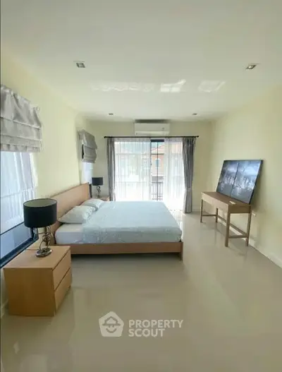 Spacious bedroom with modern decor and large windows for natural light