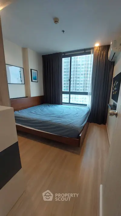 Modern bedroom with large window and wooden flooring in high-rise apartment