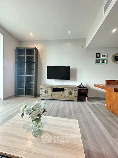 Modern living room with stylish decor and mounted TV, featuring elegant flooring and cozy ambiance.