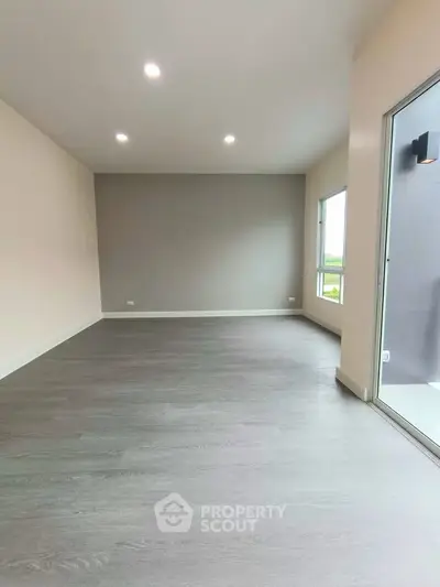 Spacious modern living room with large windows and sleek flooring.
