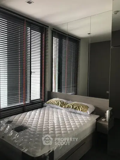 Modern bedroom with large windows and mirrored wall for spacious feel.