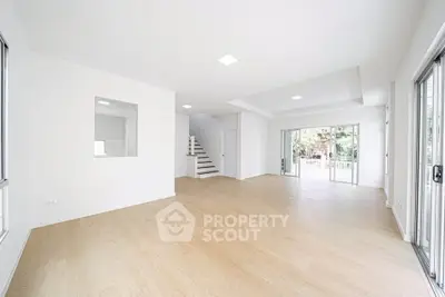 Spacious open-plan living room with large windows and modern staircase, perfect for family gatherings.