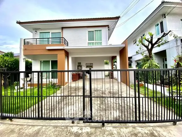 Modern two-story house with gated driveway and lush garden