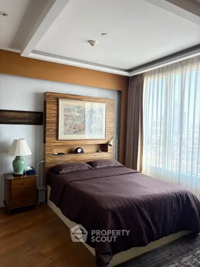 Spacious bedroom with large window and elegant decor in modern apartment.