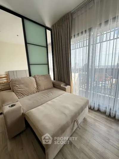 Cozy living room with plush sofa and large windows offering natural light and city view.